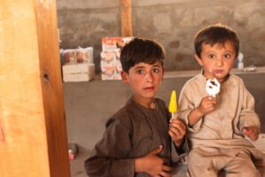 Zwei afghanische Kinder genießen ein Eis auf dem grenzüberschreitenden Markt von Shohun im Tal des Flusses Piandj in Tadschikistan.