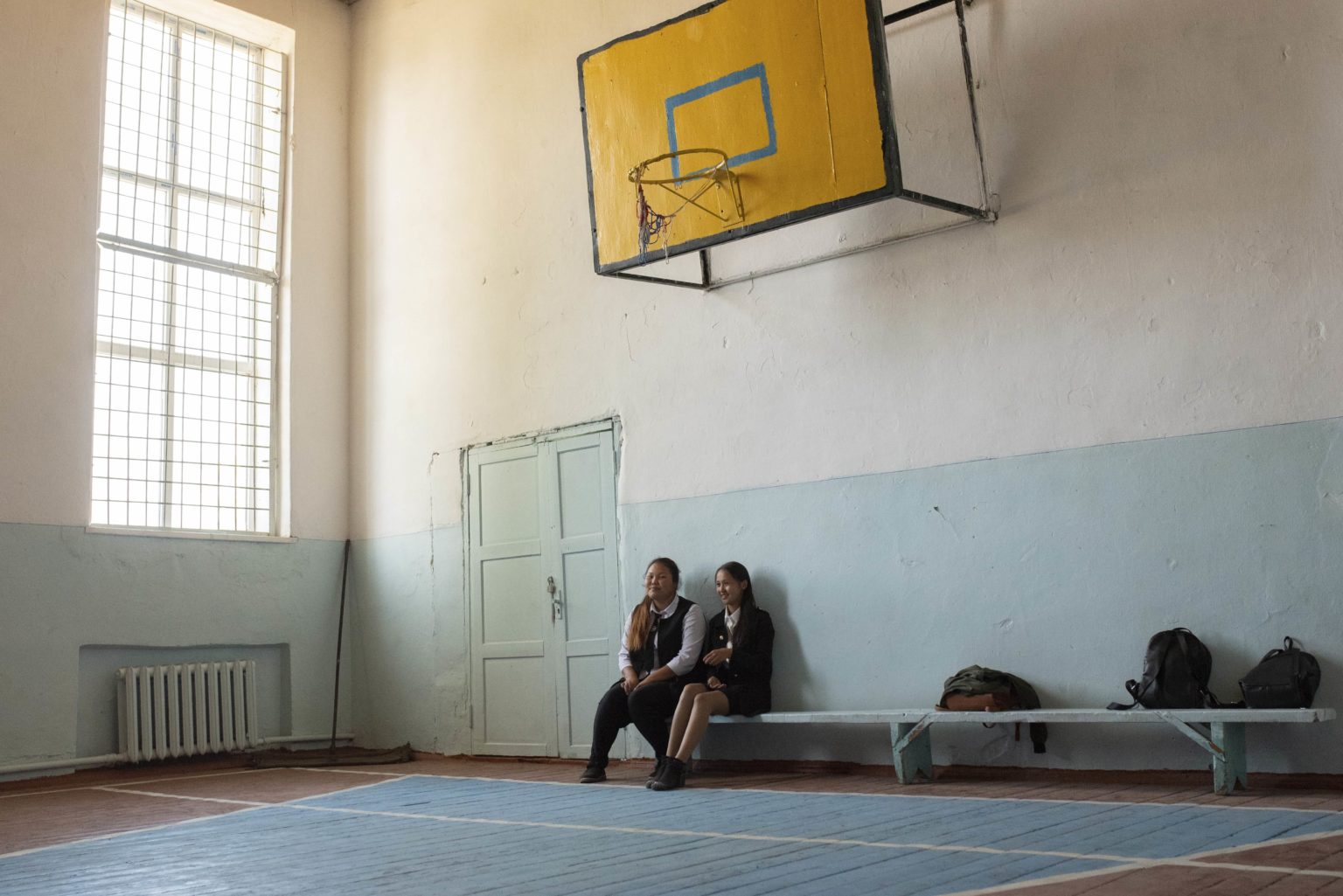 Two girls sit in a sports hall in Kyrgyzstan