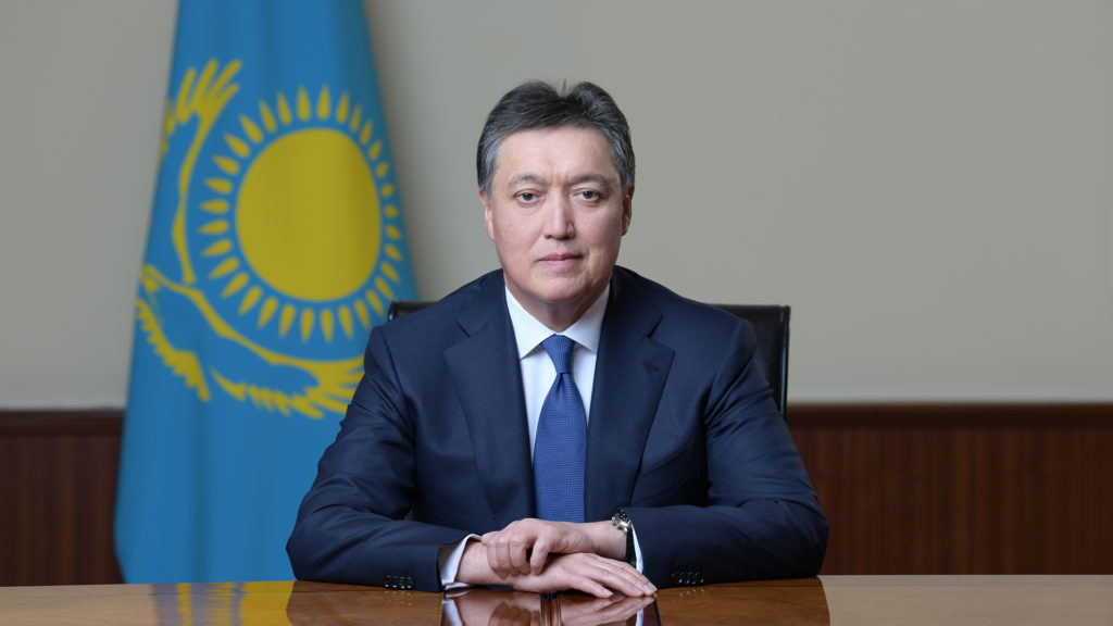 Aqar Mamin, prime minister of Kazakhstan, sitting in front of the flag of Kazakhstan