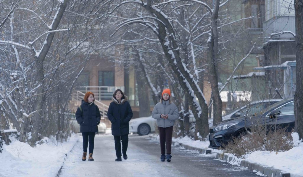 Still from the film The Wife: three women walking in a city in winter