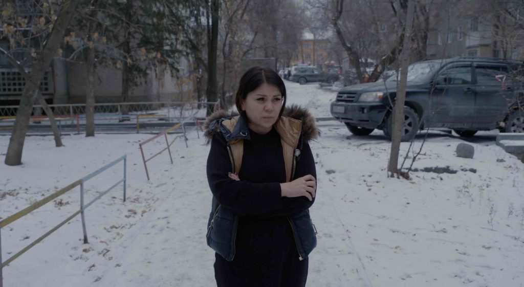 Still from the film The Wife: a woman standing outside, surrounded by snow