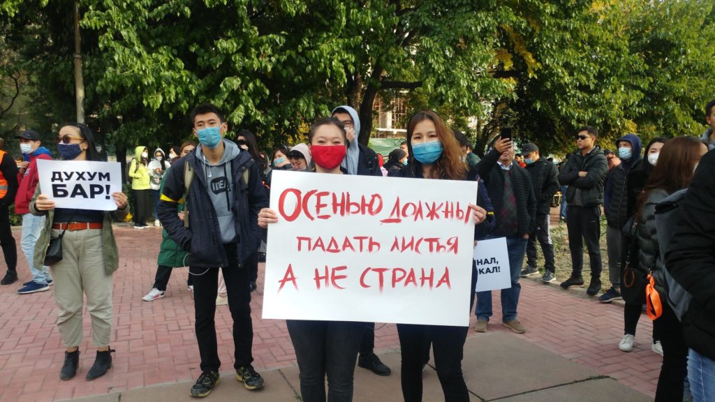 Two women hold a placard at a demonstration in Kyrgyzstan: "In autumn, leaves should fall, not the country".