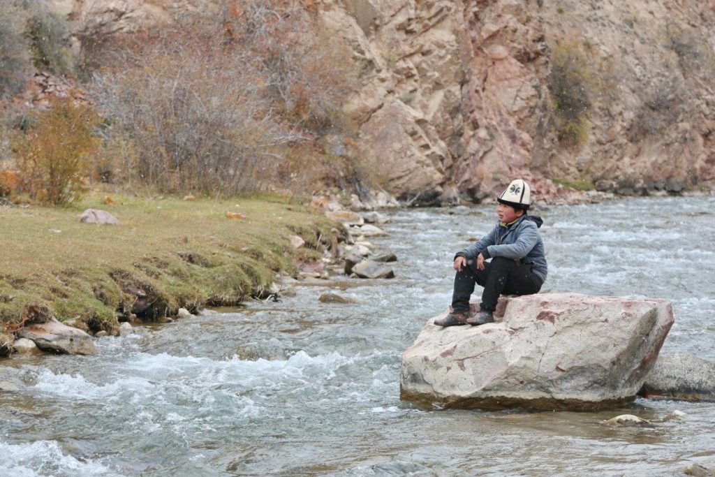 Daniyar Koichubeko sitting on a rock in the Naryn River