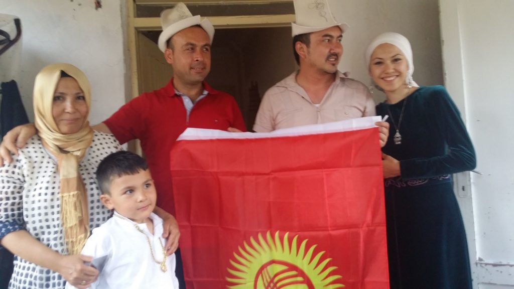 A Van Kyrgyz family pose for a photo with the Kyrgyz flag.