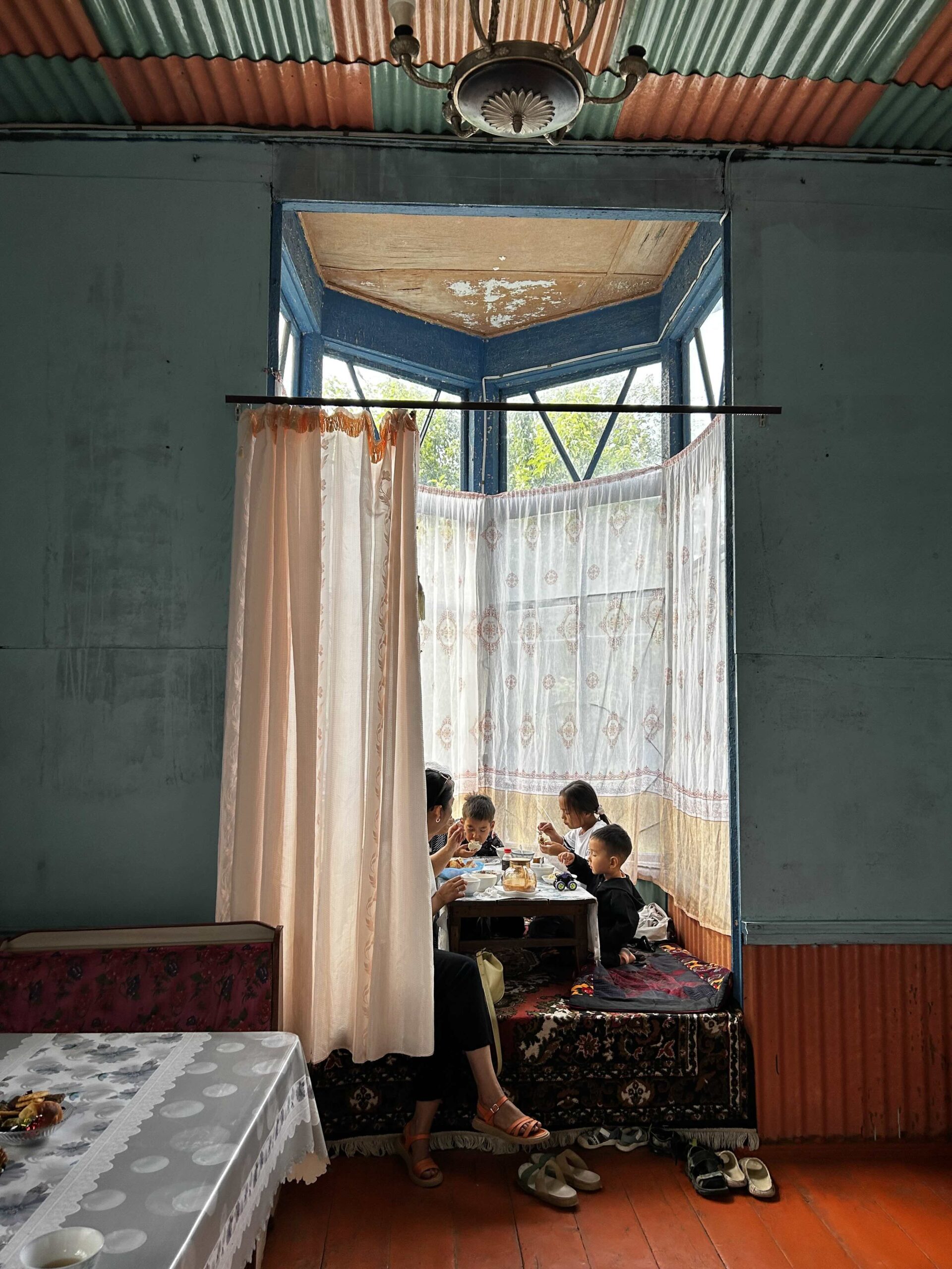 A mother is quietly eating with her three children in the semi-abandoned sanatorium of Jeti Ögüz