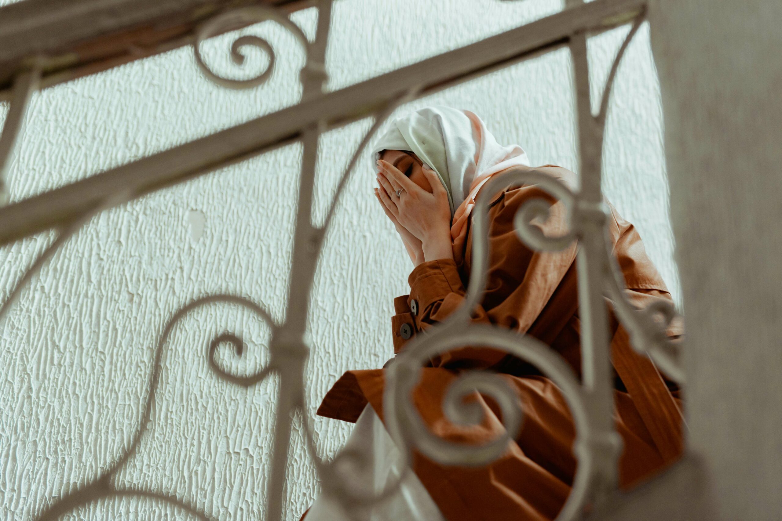 Woman sitting on a stairs with her hands covering her face.