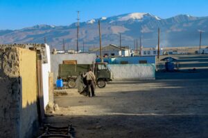 a man with his back to a street in a Tajik village autumn sunshine