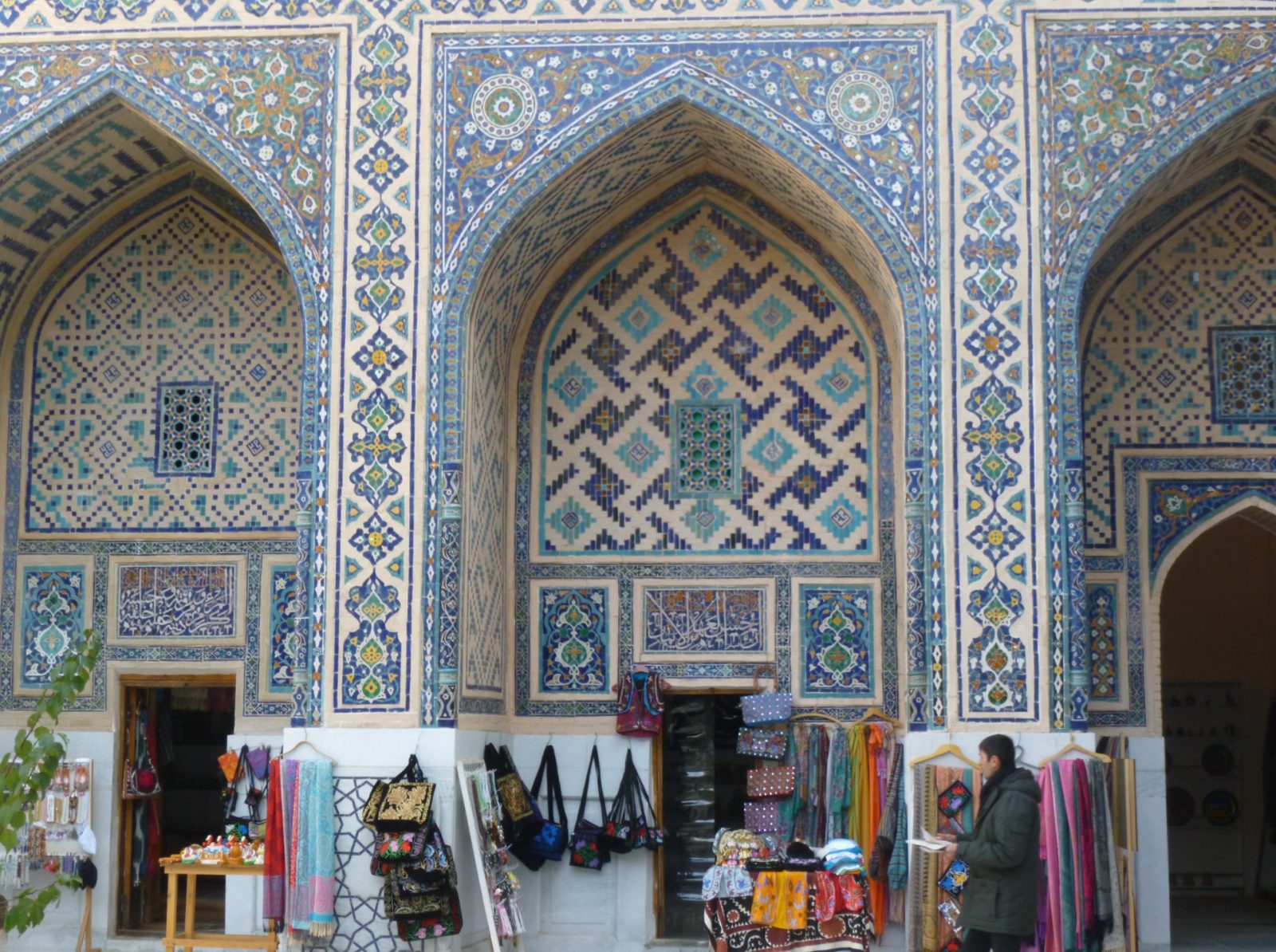 Traditional crafts displayed beneath the tiled arches of a historic madrasa in Bukhara, Uzbekistan. Credits: Mathieu Lemoine.