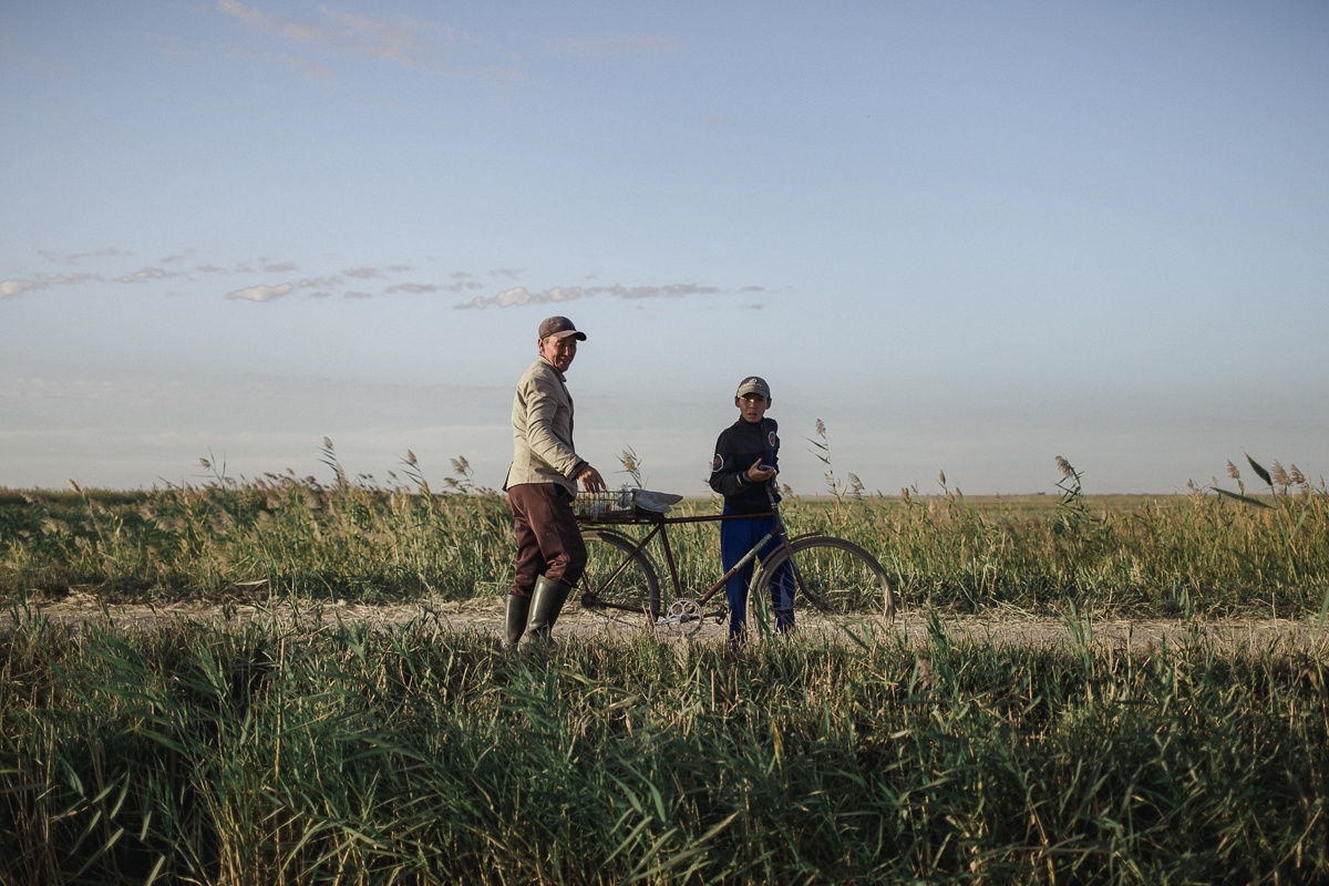 Un vieil homme et son petit-fils a velo au le long d'une route, au Kazakhstan.