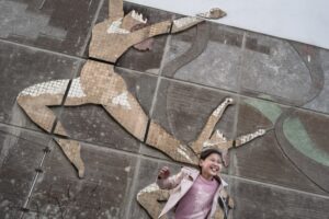 In a micro district of Bishkek, a little girl plays flying in front of the decor of a bygone era. ©MaryliseVigneau