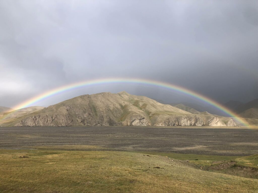 Un arc-en-ciel s'étire au dessus des monts du camp de yourtes de Kel-Sou.