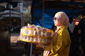 jeune femme avec des lunettes de soleil portant un grand plateau de gâteaux